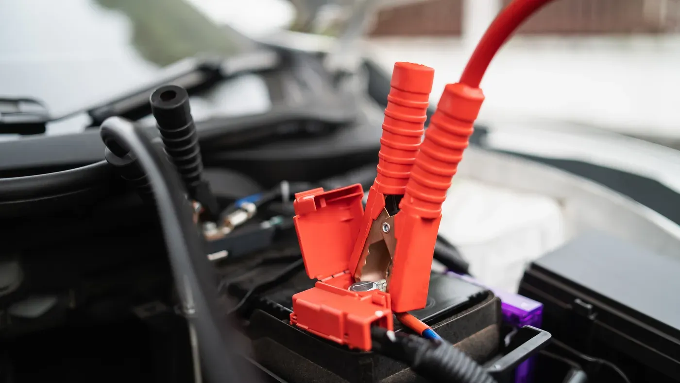 Batteriladdare kopplad till ett bilbatteri i motorrummet